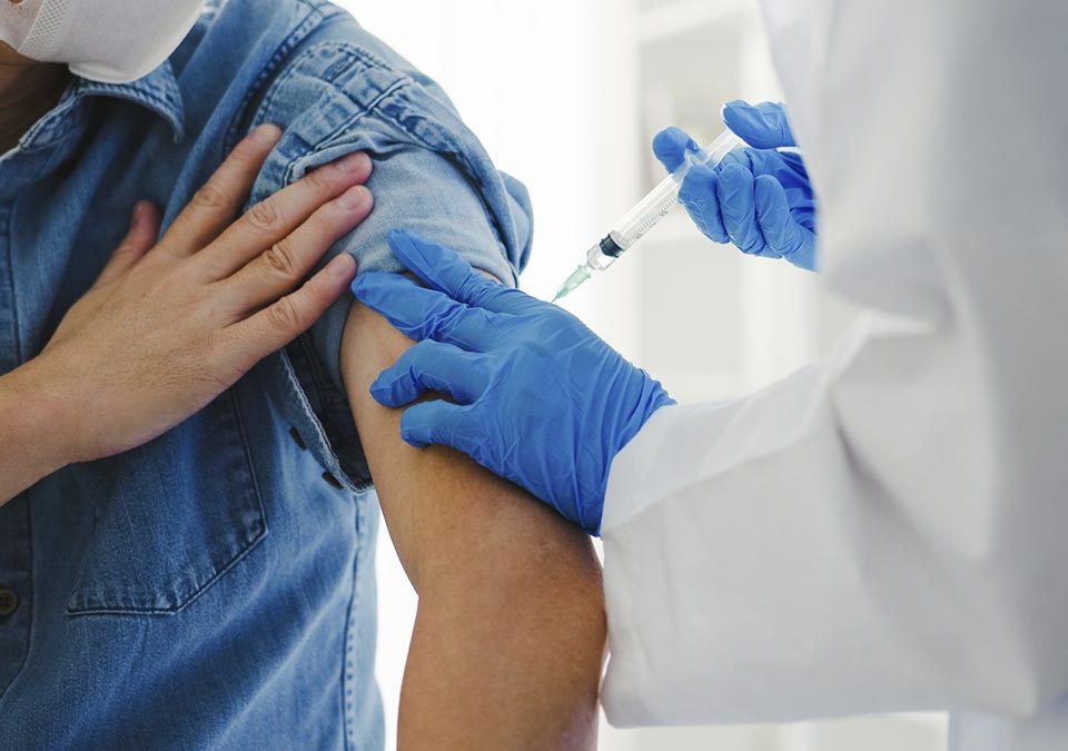 Médico aplicando vacina em braço de paciente